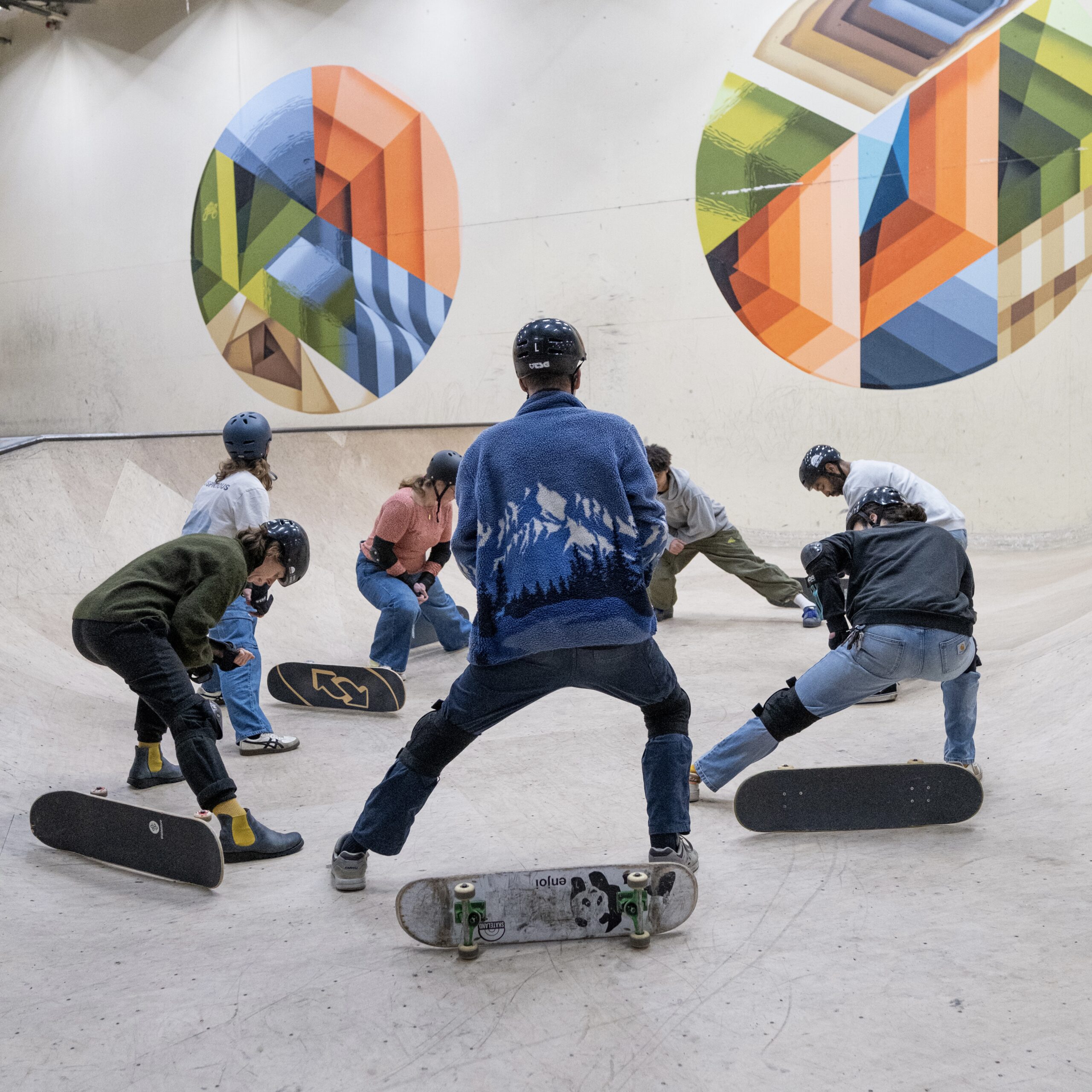 Deelnemers doen een warming-up en oefenen techniek tijdens een skateboardles