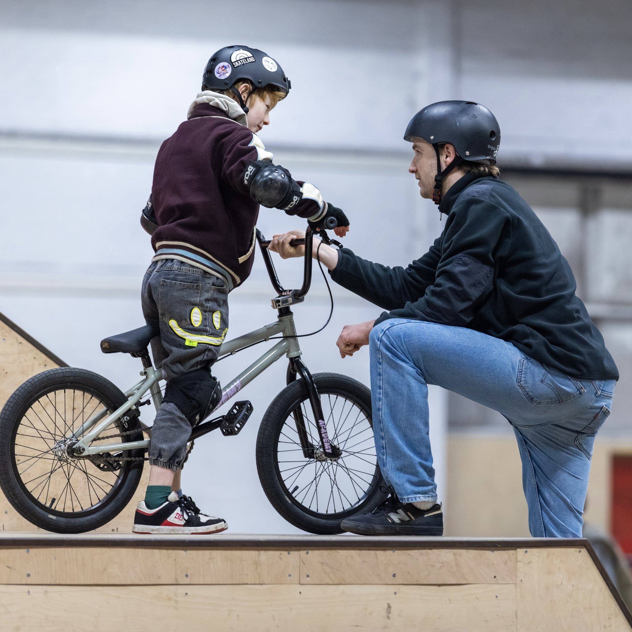 Instructeur helpt een kind tijdens een BMX-les op een ramp