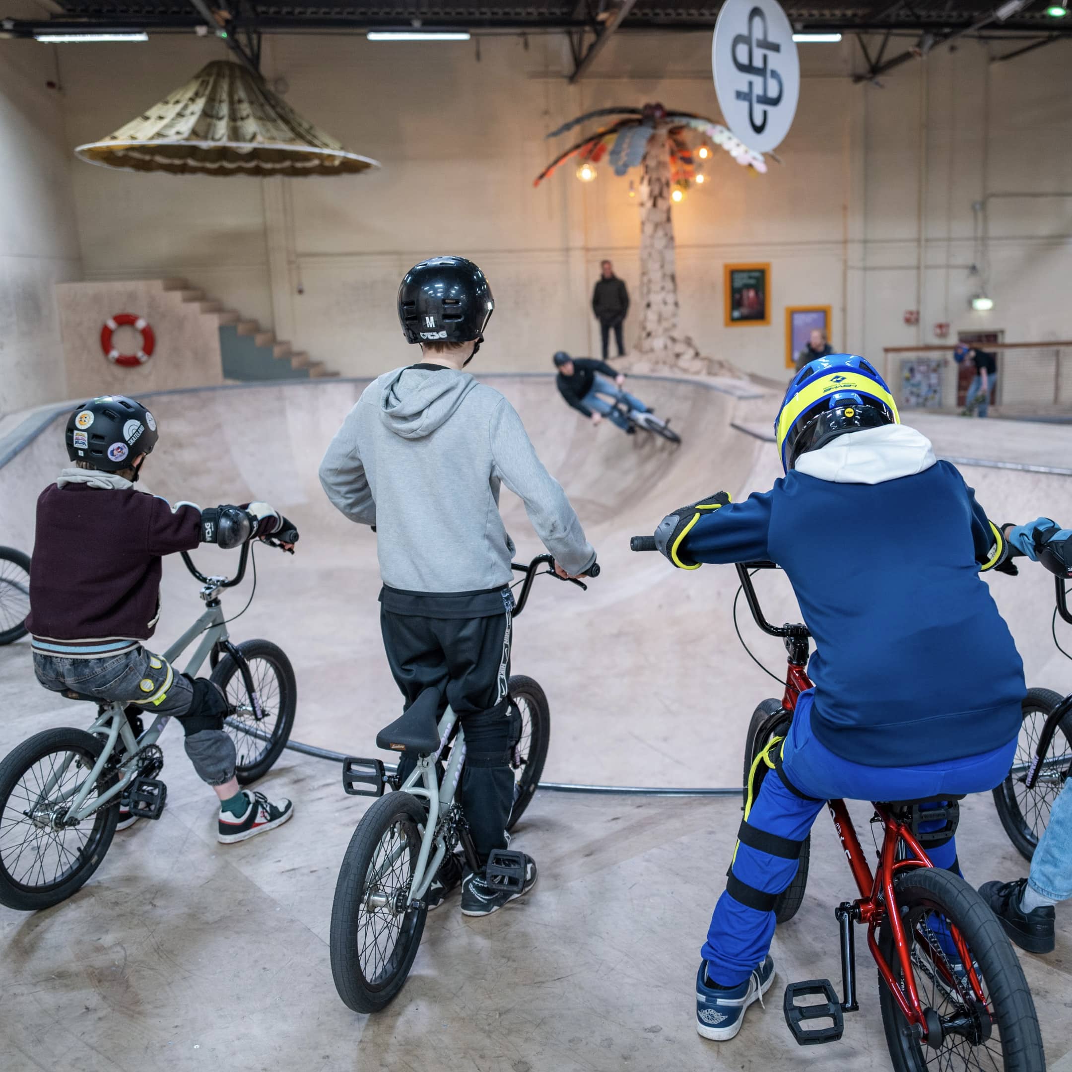 Deelnemers tijdens een BMX-les oefenen in de bowl van het indoor skatepark