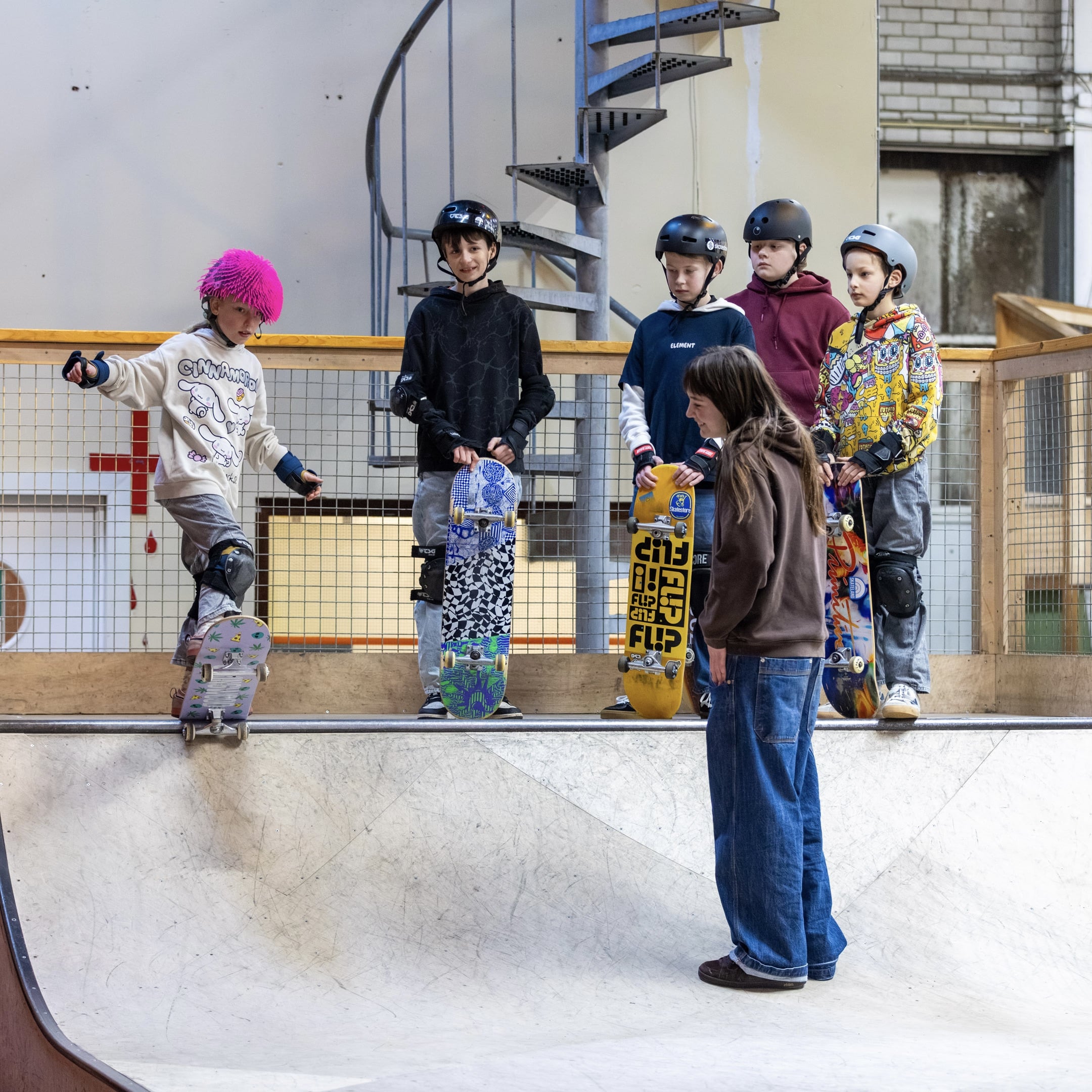 Kind oefent een drop-in met begeleiding van een instructeur tijdens een skateboardles